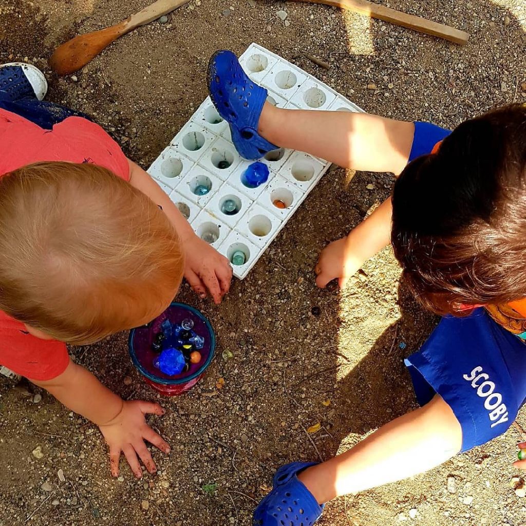 Toddlers playing together in the sand outdoors